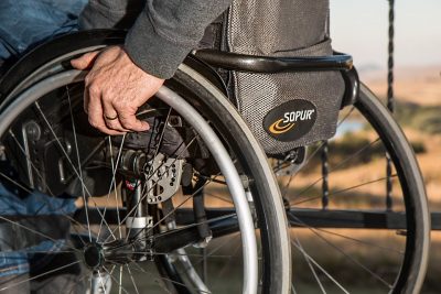 Osoba u invalidskim kolicima drži ruku na kotaču