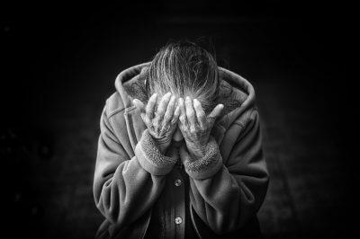 Crno-bijela fotografija umirovljenice koja se drži rukama za glavu