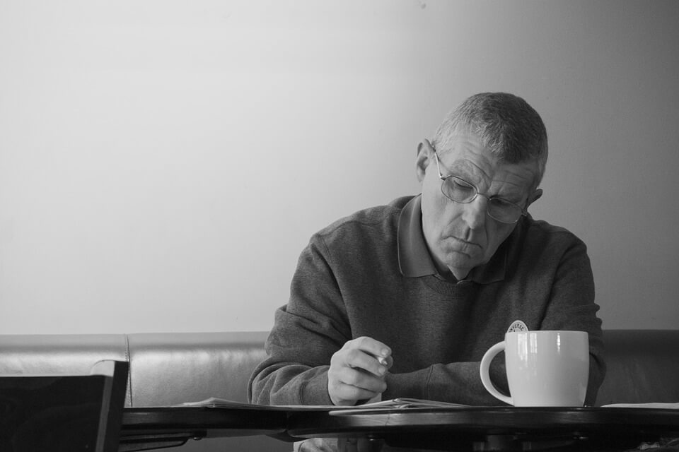 Crno-bijela fotografija muškarca koji sjedi sam