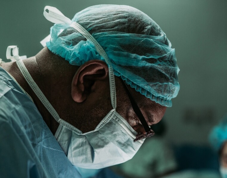 lijecnik s maskom i kapom u krupnom planu pregledava pacijenta