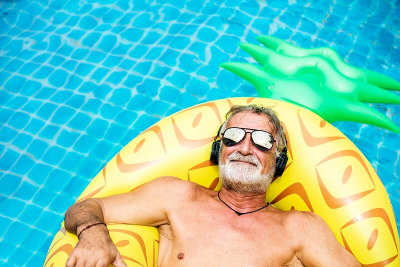 umirovljenik sa sunčanim naočalama na žutom madracu na napuhavanje