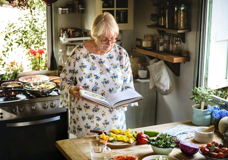 Umirovljenica gleda u kuharicu i sprema se na kuhanje