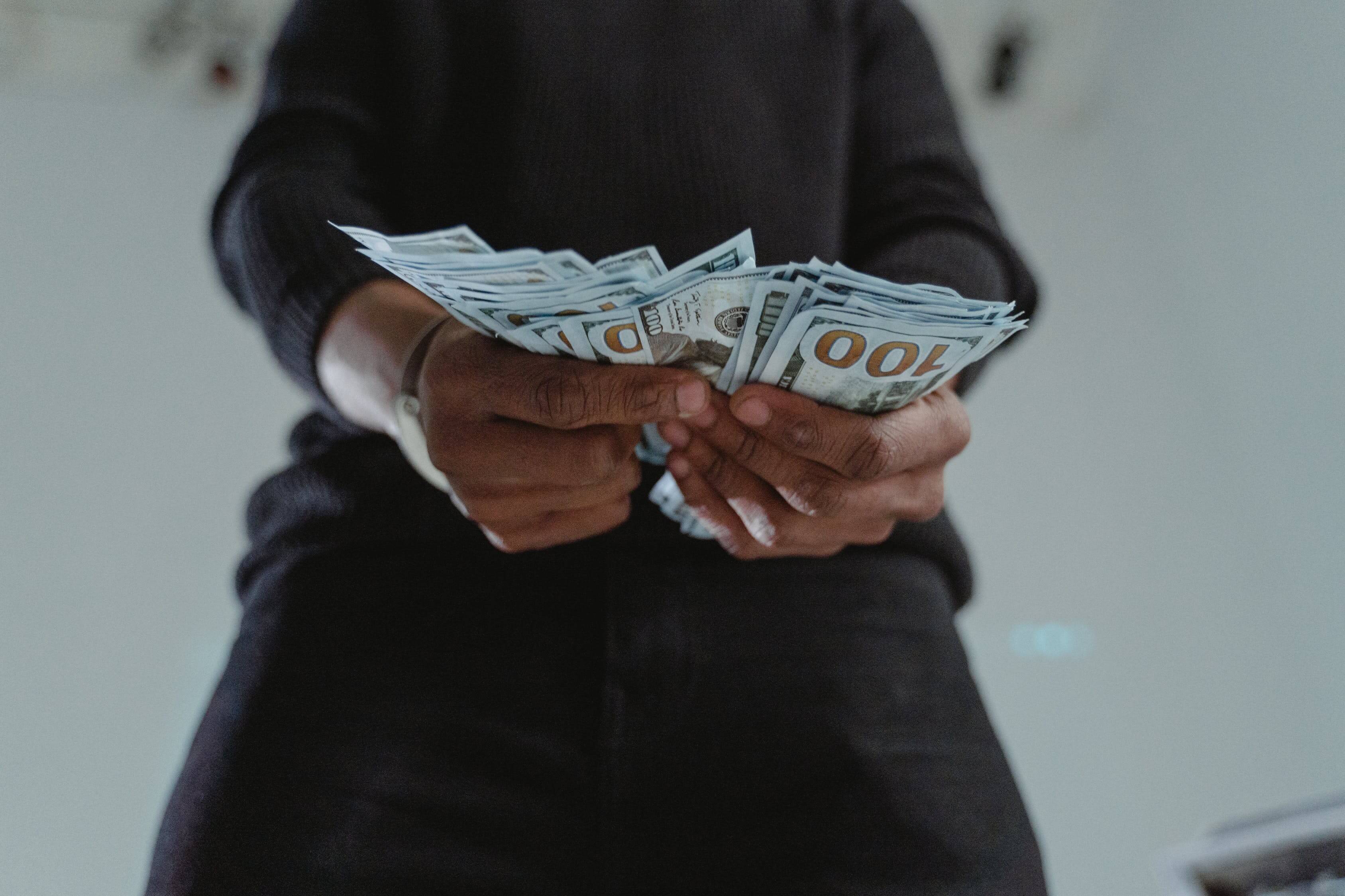 Fotografija iz žablje perspektive, gdje osoba u rukama drži veći iznos novca