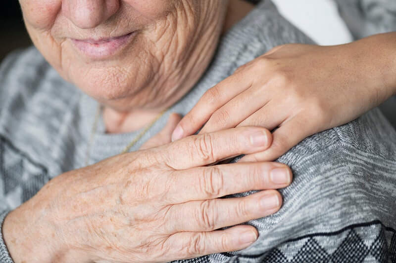 Ruka mlađe osobe na ramenu starije osobe koja gleda prema toj ruci