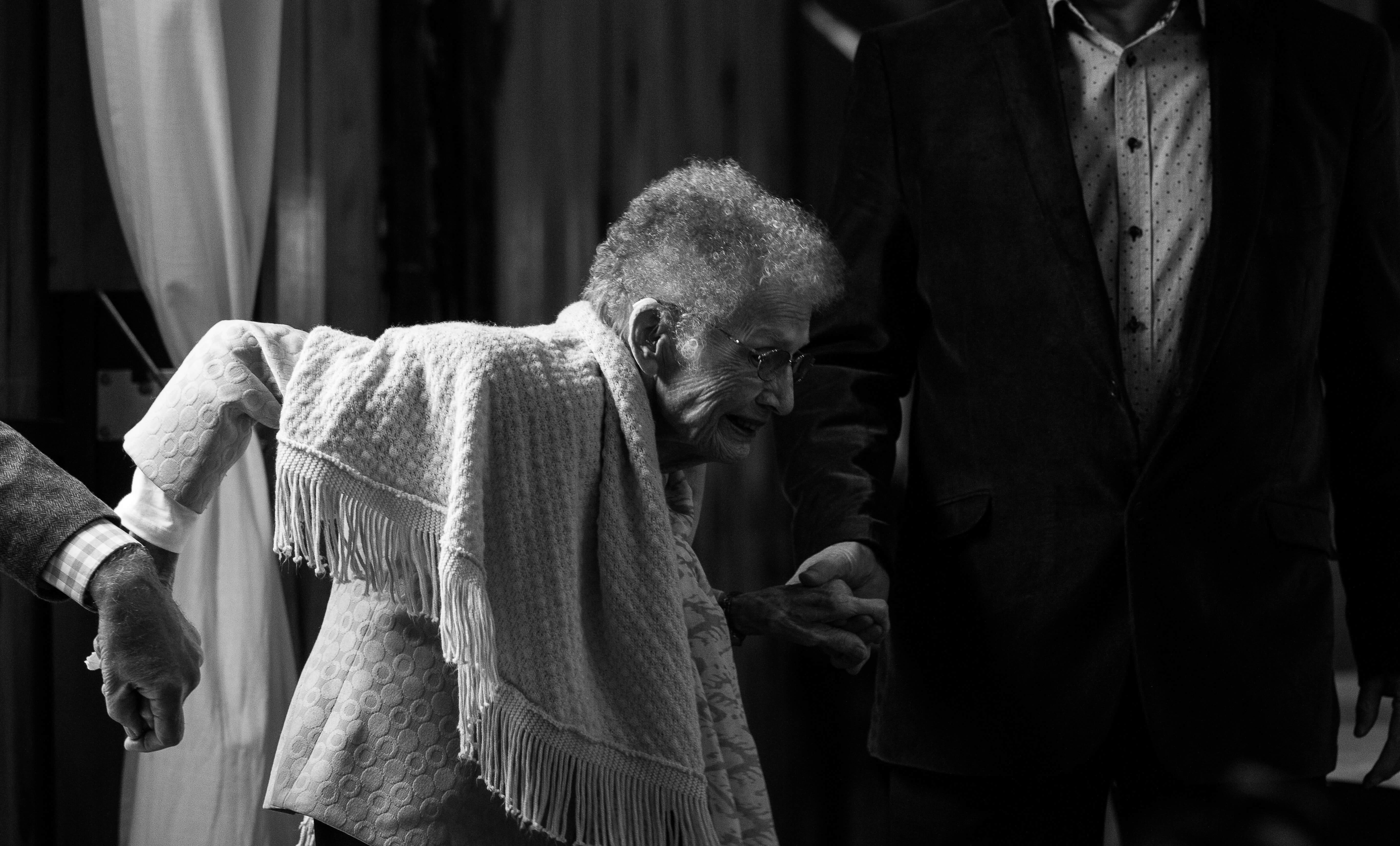 Crno-bijela fotografija starije ženske osobe kojoj dvoje pomažu kod hodanja | Unsplash