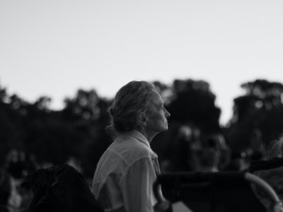 Crno-bijela fotografija starije gospođe koja sjedi na klupi