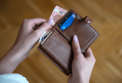 Vađenje novca iz smeđeg novčanika u kojemu se nalaze i kartice
