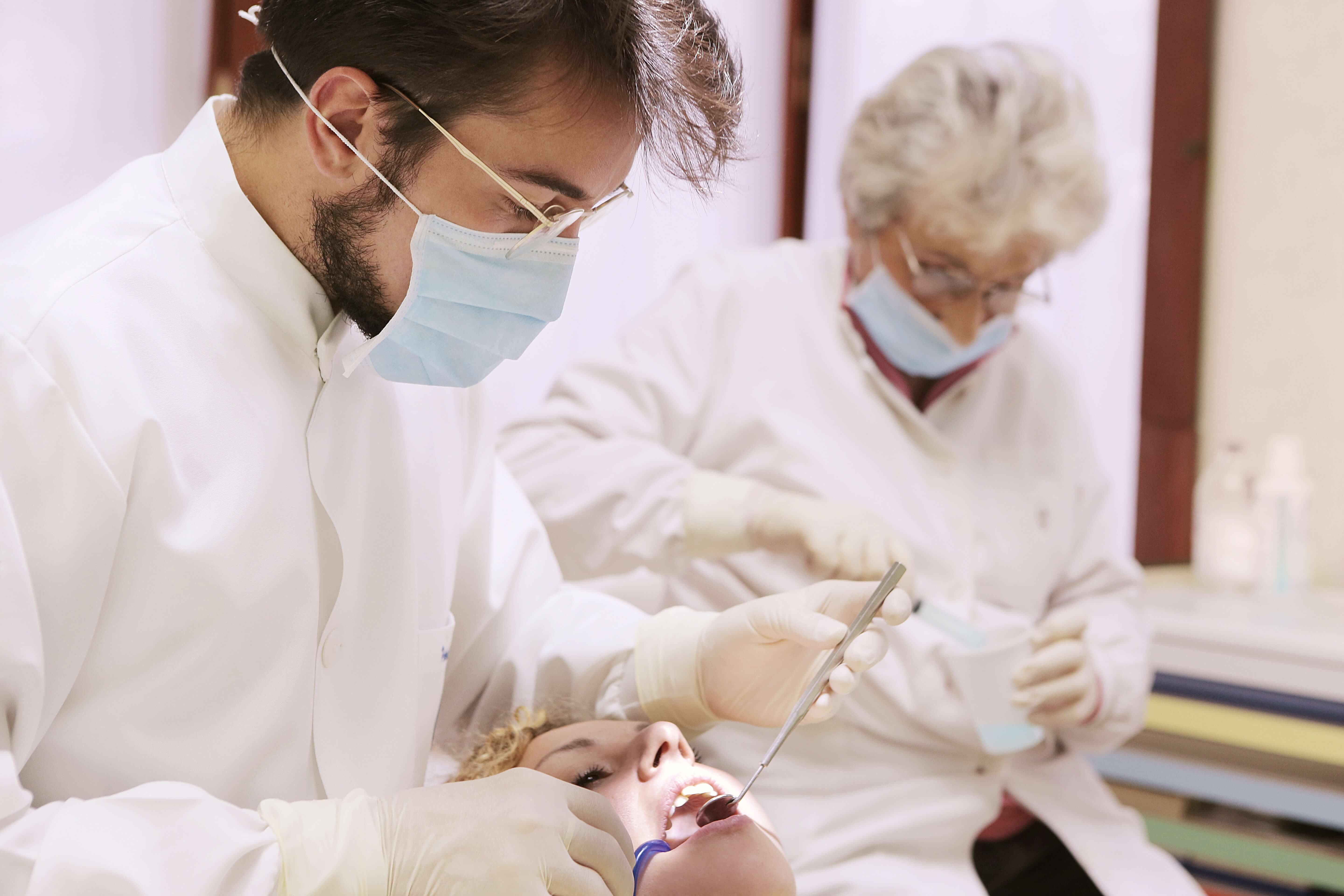 zubari pregledavaju zube pacijenta