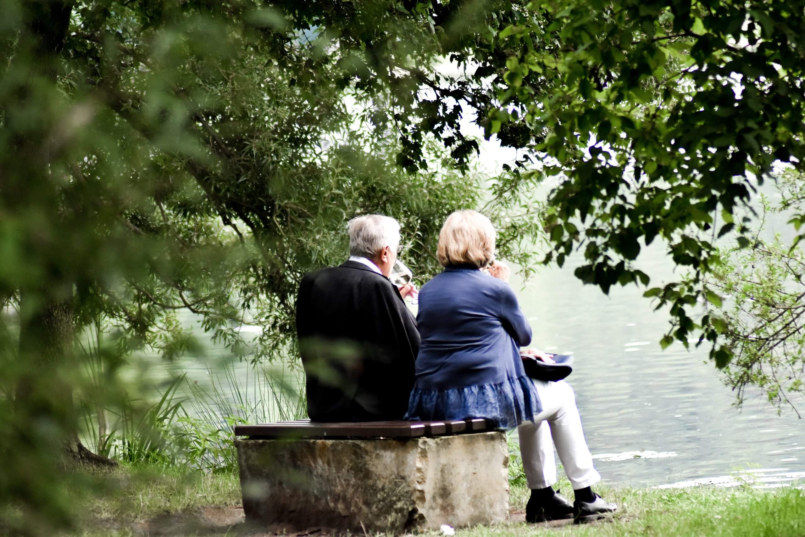 Stariji par sjedi na klupici u prirodi