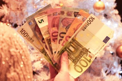 novčanice eura u rukama ispred božićnog drvca