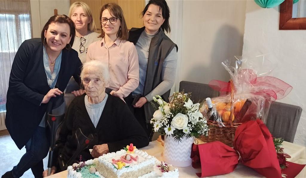 Baka Smiljana slavi svoj 104. rođendan s tortom i cvijećem ispred sebe, u društvu zaposlenica projekta Zaželi