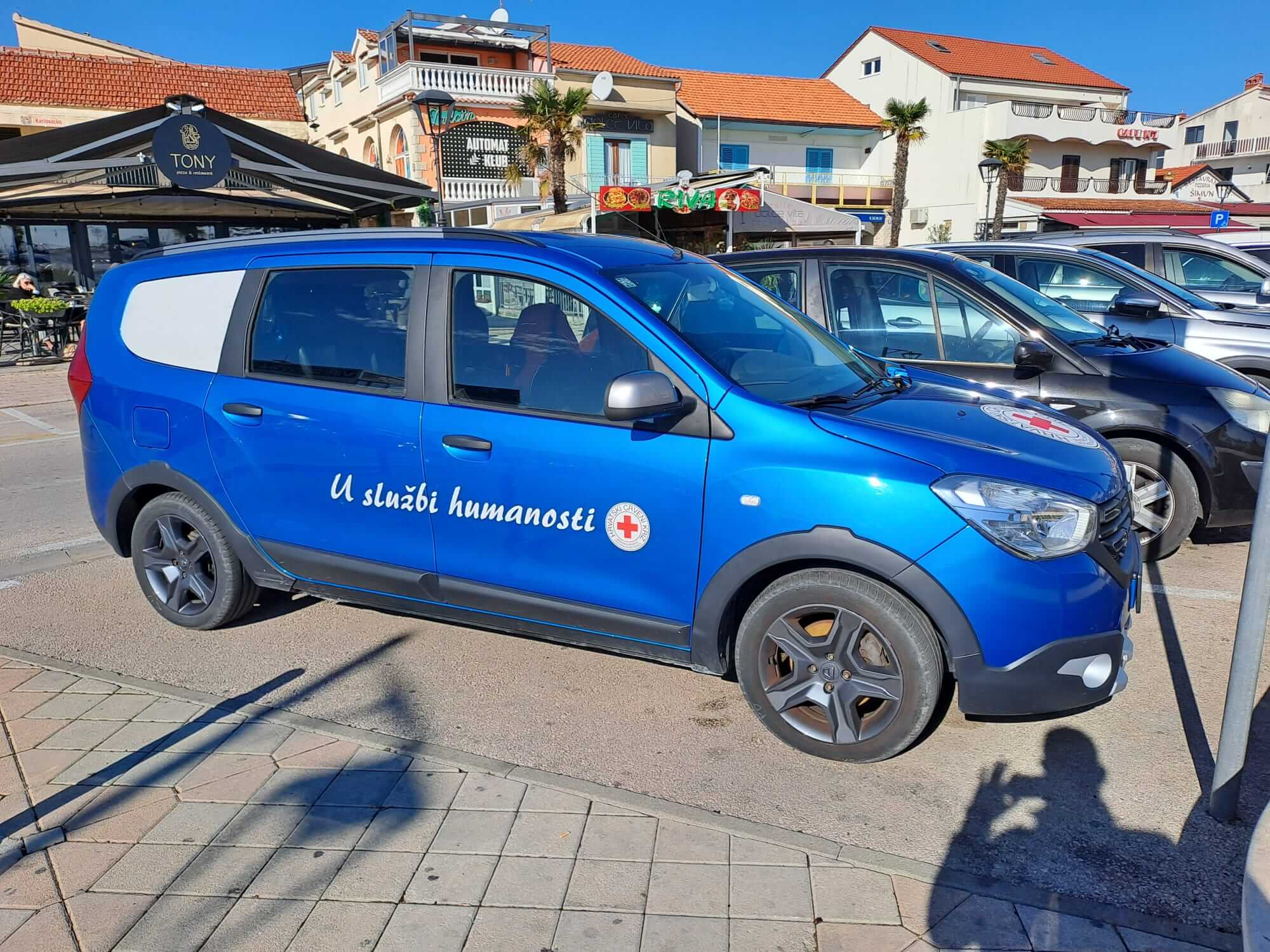 Plavi automobil s logom Crvenog križa i natpisom 'U službi humanosti'