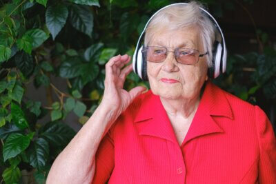 Starija ženska osoba sluša glazbu na slušalicama