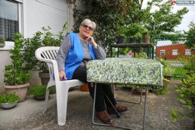 Umirovljenica Danica sjedi za stolom u svojem dvorištu