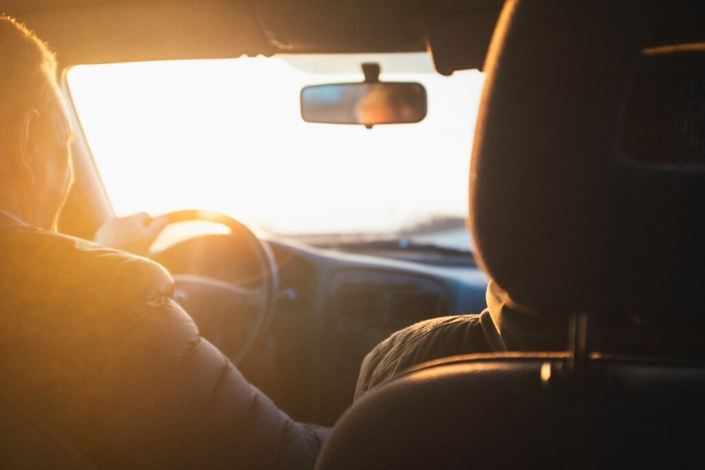 dvije osobe se voze u autu dok ih obasjava sunce