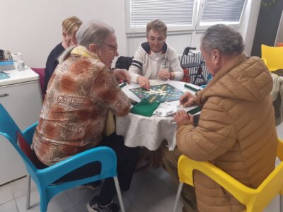 Umirovljenici sjede za stolom i igraju društvene igre