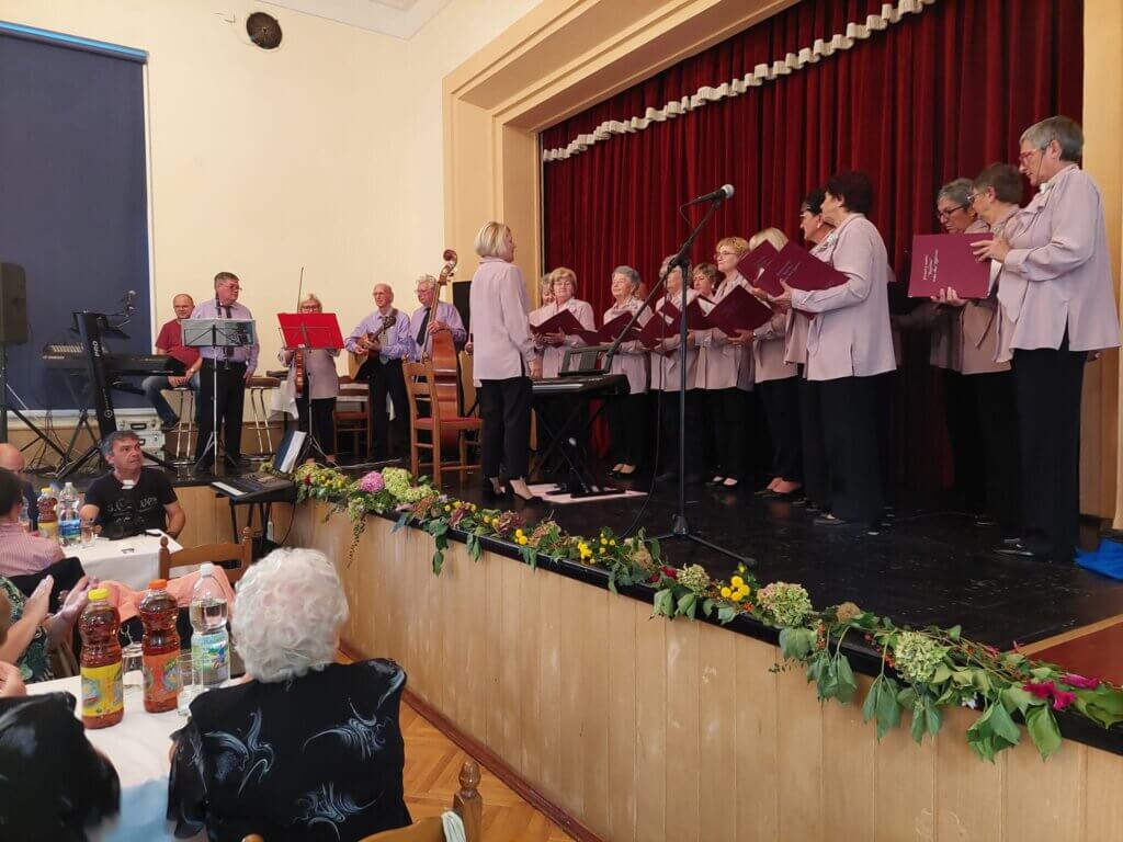Zbor Umirovljenik na pozornici pjeva u košuljama s crvenom pjesmaricom u rukama