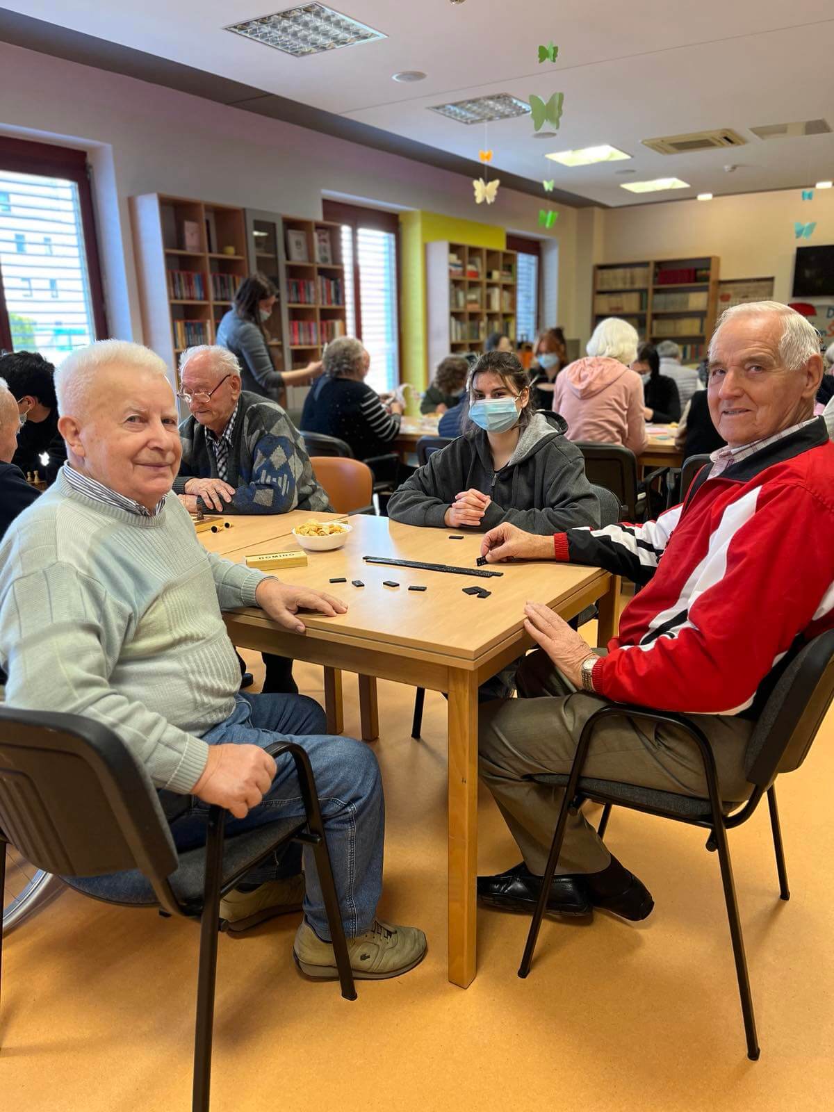 Umirovljenici i učenica igraju domino