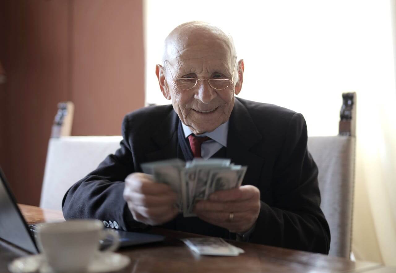 Stariji muškarac drži novac u rukama