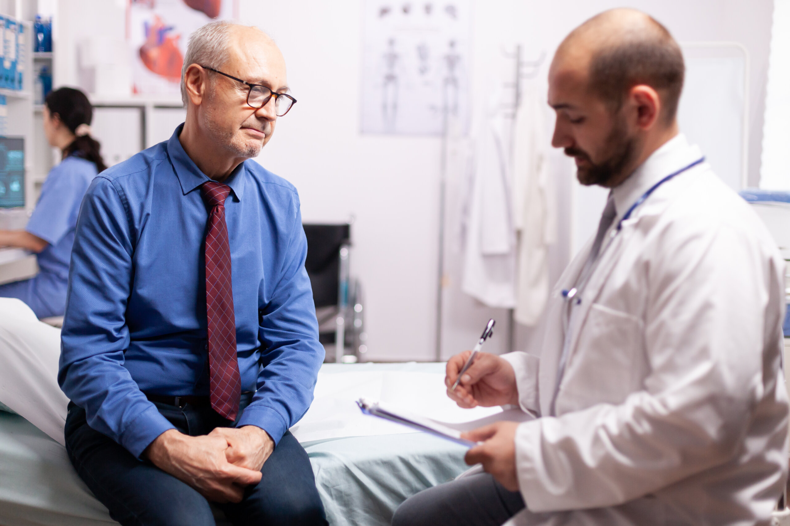 Kirurg koji nosi stetoskop razgovara o liječenju u sobi za preglede sa starijim muškarcem