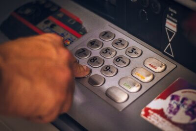 Muškarac unosi PIN na bankomatu kako bi pristupio svom računu s kojeg će mu biti povučen novac.