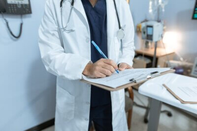 Liječnik sa stetoskopom piše po medicinskom kartonu