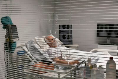 Hospitalizirani stari umirovljenik leži u bolničkom krevetu s maskom za disanje.