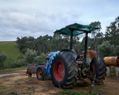 Stari plavi traktor parkiran na zemlji.
