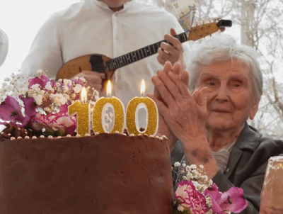 Baka Eva ispred torte sa svjećicama s brojem 100
