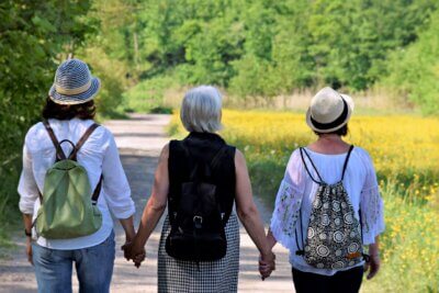 tri ženske osobe se drže za ruke u prirodi