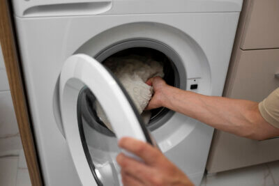 Muška ruka izvlači odjeću iz perilice rublja.