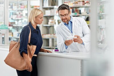 Žena u ljekarni s farmaceutom razgovara o lijeku