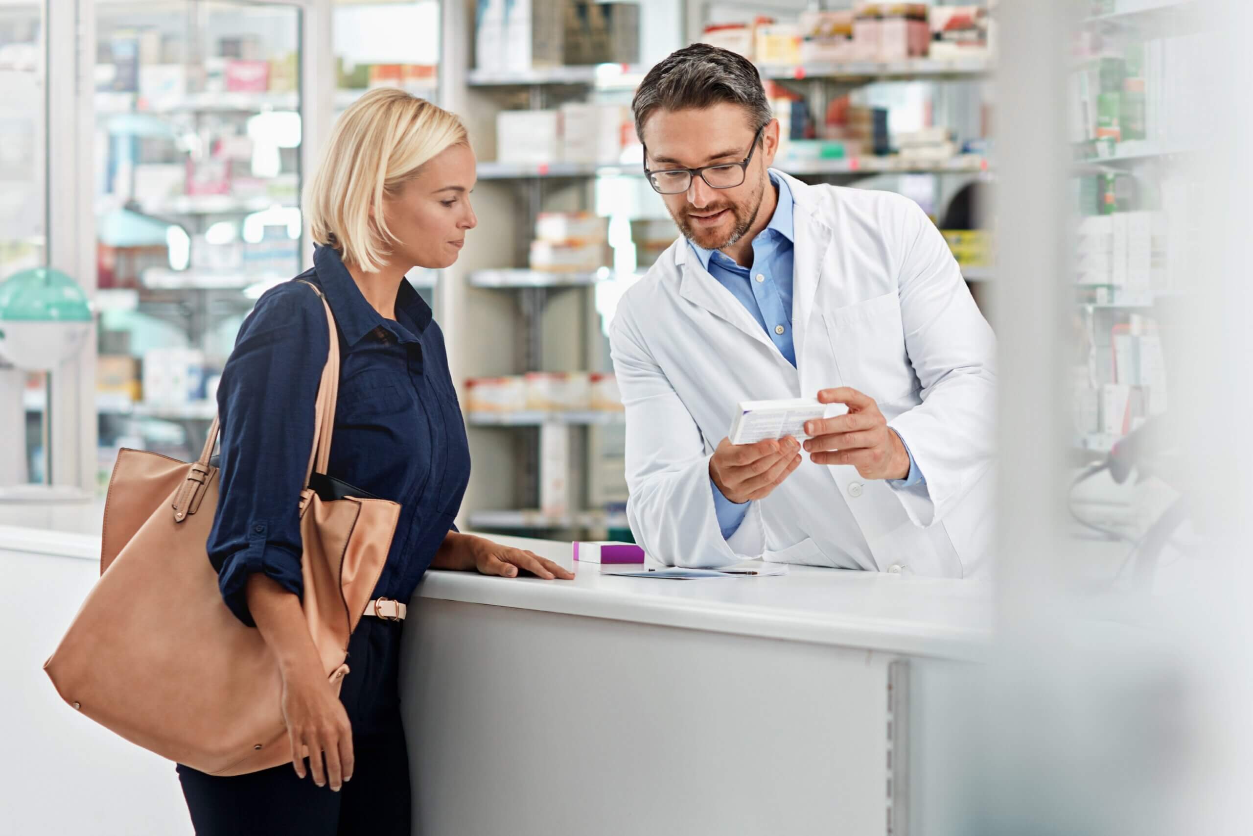 Žena u ljekarni s farmaceutom razgovara o lijeku