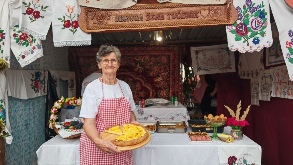 Katarina Bernardić u bijeloj majici i cvrnoj kariranoj pregači drži u ruci tanjur s jelom 'vrboavačko perje'