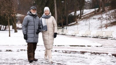 Umirovljenik i umirovljenica u zimskim jaknama na snijegu