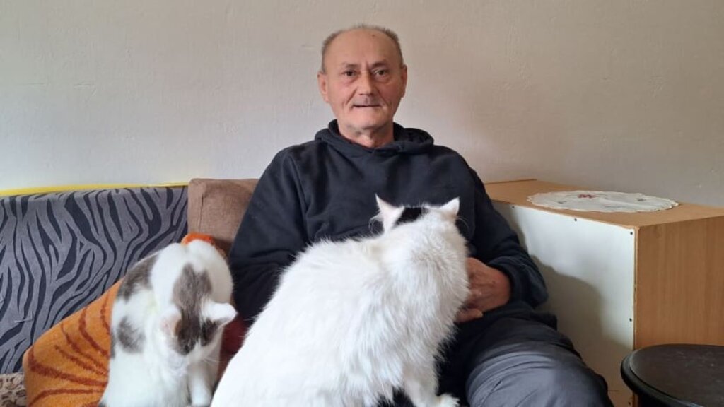 Nisvet sjedi na kauču s dvije bijele mačke