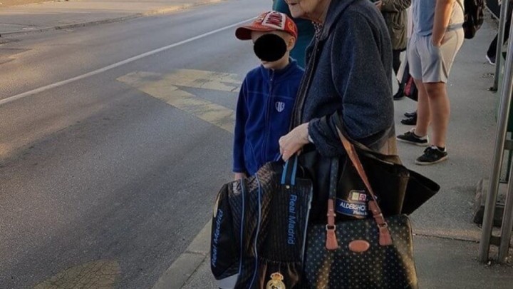Brižna baka prati svog unuka u školu noseći mu školsku torbu